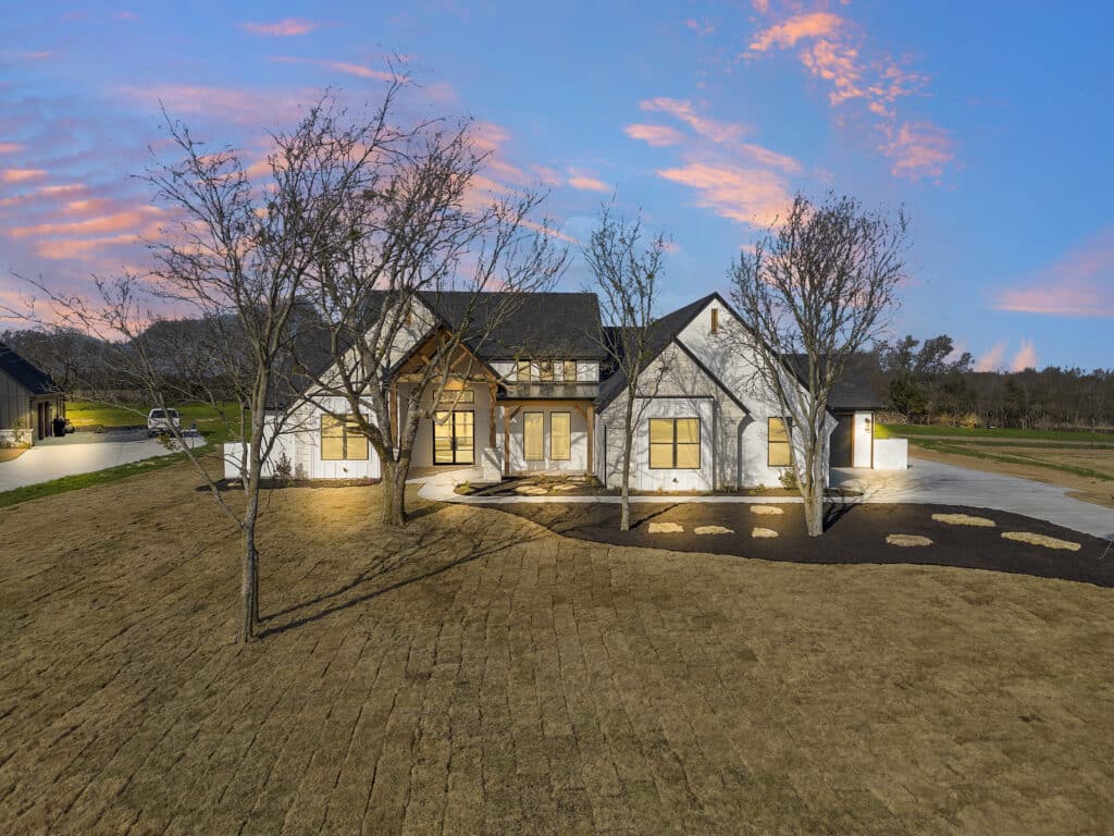 6017 Bella Terra Lane, a custom home in Godley, TX, at dusk with landscape lighting