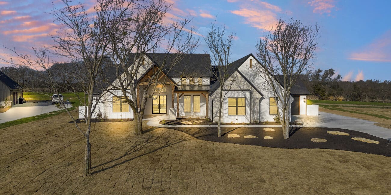 6017 Bella Terra Lane, a custom home in Godley, TX, at dusk with landscape lighting