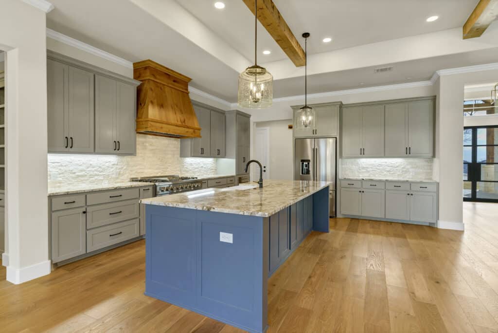 Custom kitchen with a blue granite island and cedar range hood in a Godley, TX home by SWP Custom Homes